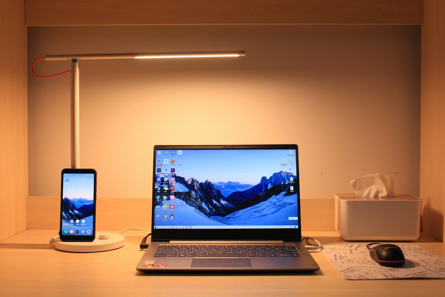 Laptop och smartphone laddas på ett träskrivbord.